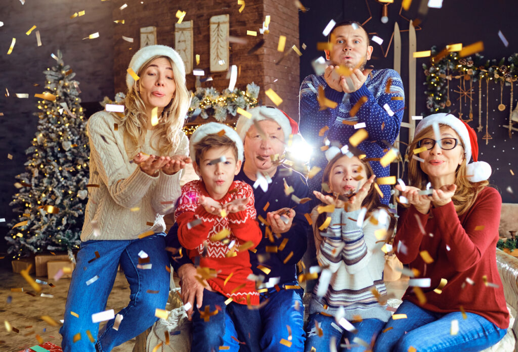Big happy family blowing confetti at home for Christmas. New Year celebration in the family.