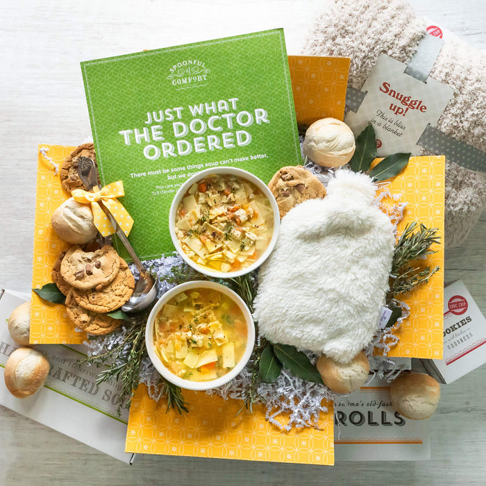 Total TLC Package: Two bowls of soup next to cookies, rolnls, a ladle, warm fuzzies warming pack, and a blanket. Insert included reads: Just what the doctor ordered