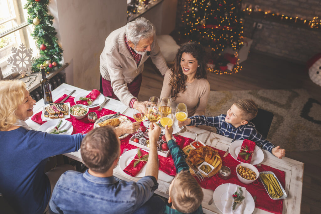 High angle view of a beautiful happy family gathered around the table, having Christmas dinner all together at home, celebrating Christmas and making a toast