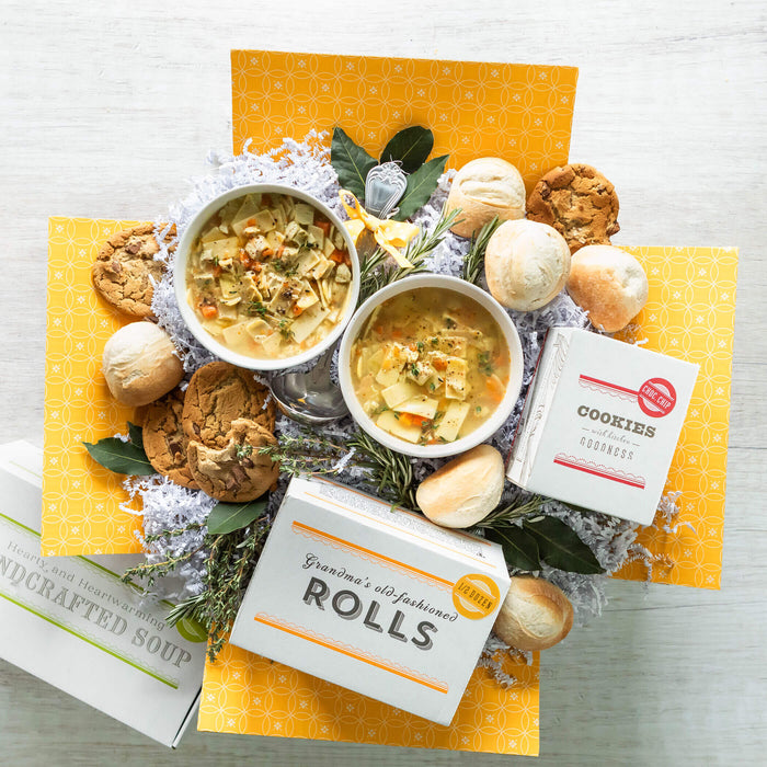Soup Box with two bowls of soup surrounded by cookies, rolls, ladle and cookies and roll boxes.